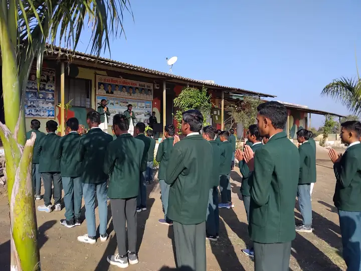 Boys in green blazers stand in lines for morning assembly in front of the school building.